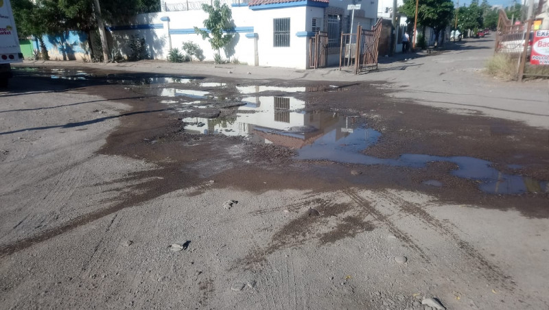 Calle de los peninos con aguas negras y llena de baches