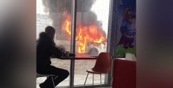 #Video Joven disfruta de un café a pocos pasos de un autobús en llamas