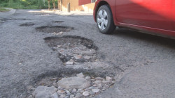 Profundos baches sobre la calle del parque