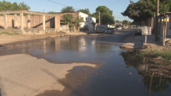 Aguas negras que recorren un camino por detrás de las casas..