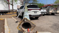 Cae lámpara de alumbrado público encima de dos camionetas